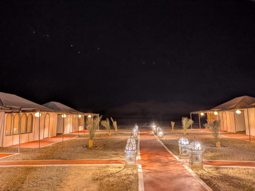 Grand Dune desert camp glowing beneath the night sky